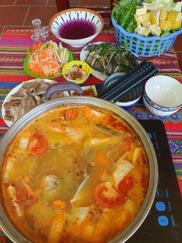 a pot of soup sitting on a table with food at Cyan Sapa Homestay in Sa Pa