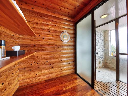 um quarto com paredes de madeira e um relógio na parede em Nagahama Beach Resort Kanon em Nakijin