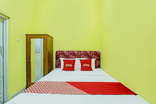 1 dormitorio con 1 cama con 2 almohadas rojas en OYO 92792 Umi Rahayu Guesthouse, en Semarang