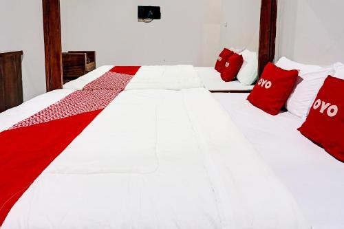 a large white bed with red pillows on it at Hotel O Juanda Homestay Syariah in Pasuruan