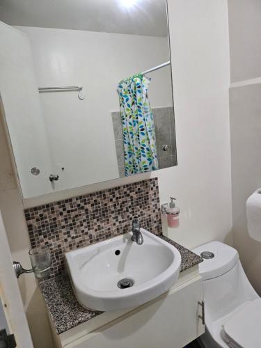 a bathroom with a sink and a toilet and a mirror at Blue Jay 618 in Bacolod