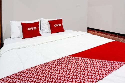 a bed with red and white sheets and pillows at Hotel O Juanda Homestay Syariah in Pasuruan
