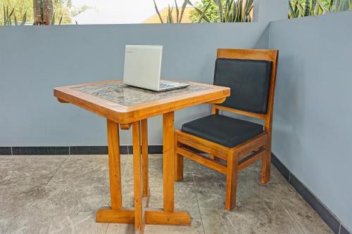 a wooden desk with a chair and a laptop on it at Hotel O Juanda Homestay Syariah in Pasuruan