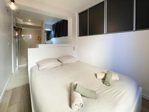 - une chambre avec un lit blanc et 2 chaussons dans l'établissement Le caroubier, à Beausoleil