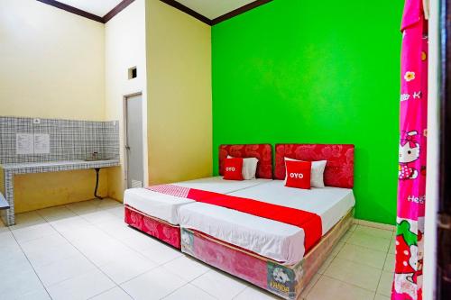 Un dormitorio con una pared verde y una cama en OYO 91583 D’cost Green Syariah en Tambak-kidul