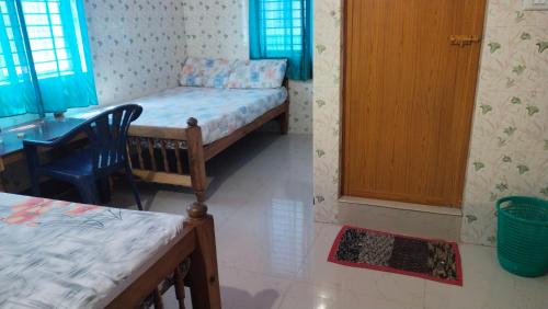 a room with a bed and a desk and a table at Happy Tourist Home and Dormitory Neyyardam in Parattipalli
