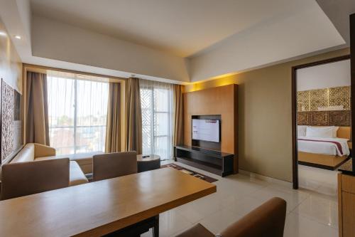 a hotel room with a dining table and a bedroom at Horison Ultima Seminyak Bali - CHSE Certified in Seminyak