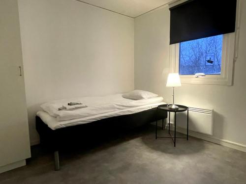 a bed in a room with a lamp and a window at Frost Longstay Lombiavägen in Kiruna