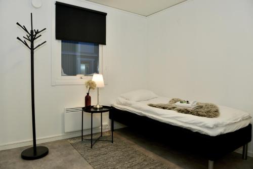 a white bedroom with a bed and a window at Frost Longstay Lombiavägen in Kiruna