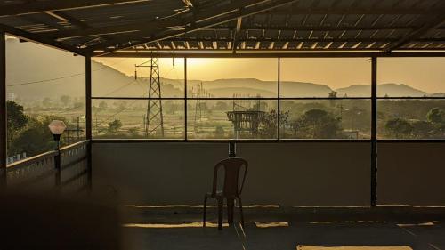 une chaise assise dans une pièce avec vue sur un champ dans l'établissement Blue Bell Homestay, à Lonavala