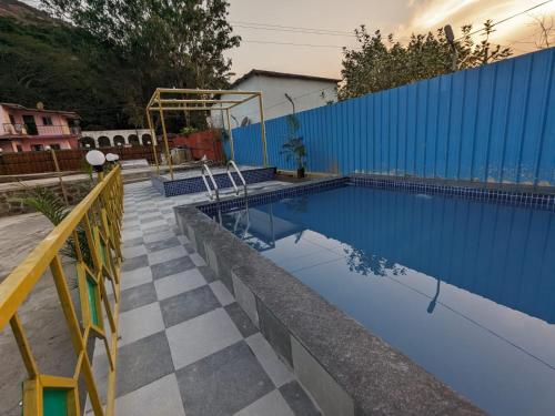 a swimming pool with a blue wall and a tile floor at Blue Bell Homestay in Lonavala
