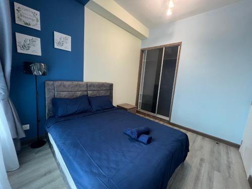 a bedroom with a bed with blue sheets and a window at Cubic Botanical KL Bangsar Entire Unit Parking/Pool in Kuala Lumpur