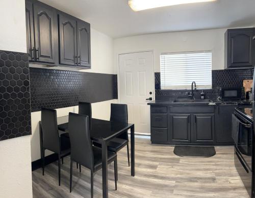 a kitchen with black cabinets and a black table and chairs at Cozy and Spacious Home in Las Vegas