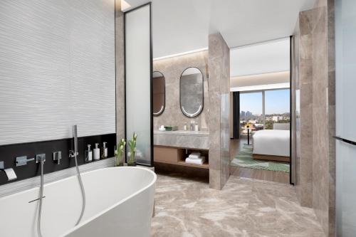 a bathroom with a tub and a bedroom at Holiday Inn Quanzhou Donghai, an IHG Hotel in Quanzhou