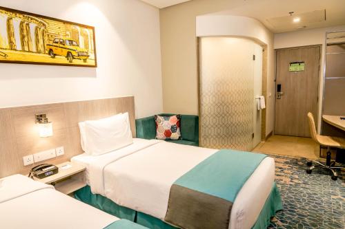a hotel room with two beds and a desk at Holiday Inn Express Kolkata Airport by IHG in Kolkata