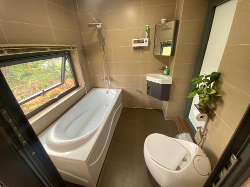 La salle de bains est pourvue d'une baignoire, de toilettes et d'un lavabo. dans l'établissement THE LAND OF LOVE Homestay - Venuestay, à Dak Lak