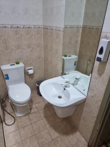 La salle de bains est pourvue de toilettes blanches et d'un lavabo. dans l'établissement Marhabaa hotel, à Sayḩ adh Dhabi