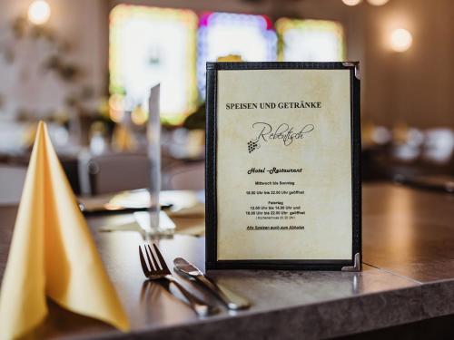 - un menu en haut d'une table avec des ustensiles dans l'établissement REBENTISCH - HOTEL Ferienwohnungen Restaurant, à Hasselfelde