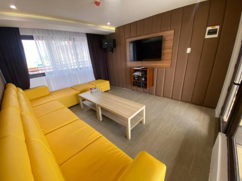 sala de estar con sofá amarillo y mesa en Red Iron Hotel, en Calbayog