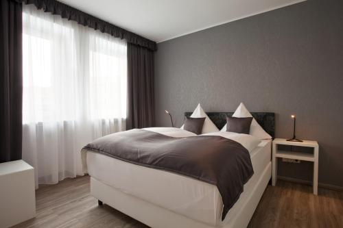 a bedroom with a large white bed with a window at Hotel Asahi in Düsseldorf