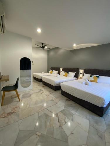 a room with two beds and a chair in it at IPOH LYL EVERGREEN HOMESTAY 12pax in Ipoh