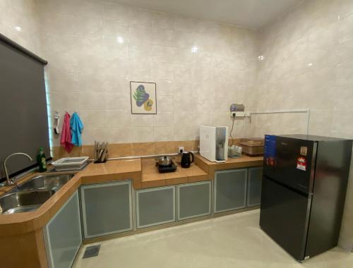 a kitchen with a black refrigerator and a sink at IPOH LYL EVERGREEN HOMESTAY in Ipoh