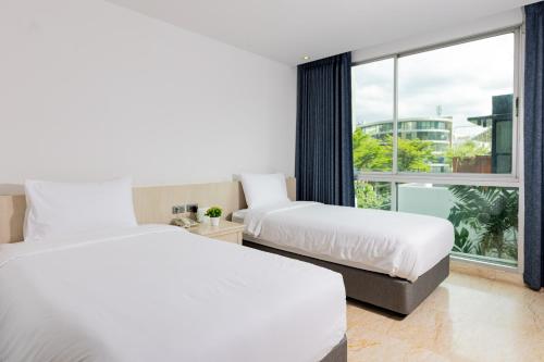 2 Betten in einem Hotelzimmer mit Fenster in der Unterkunft Sukhothai Residence Ruam Ruedi in Bangkok