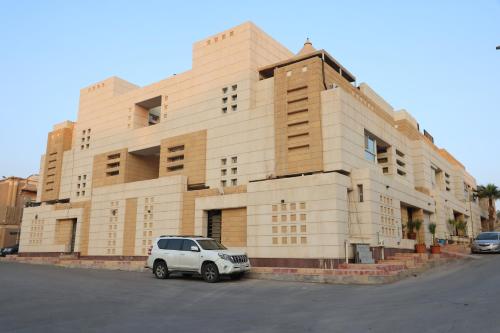 ein weißes Auto, das vor einem Gebäude parkt in der Unterkunft Sands Inn Hostel in Riad