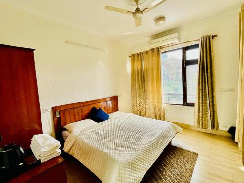a bedroom with a bed with blue pillows and a window at Hotel Suryadev in Pālampur