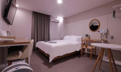 チョンジュにあるCheongju Hotel Dictionaryの白いベッドと鏡が備わるホテルルームです。