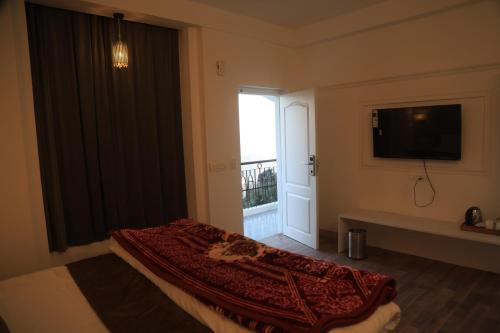 a bedroom with a bed and a television and a window at The Whispering Pine and Suites in Mussoorie