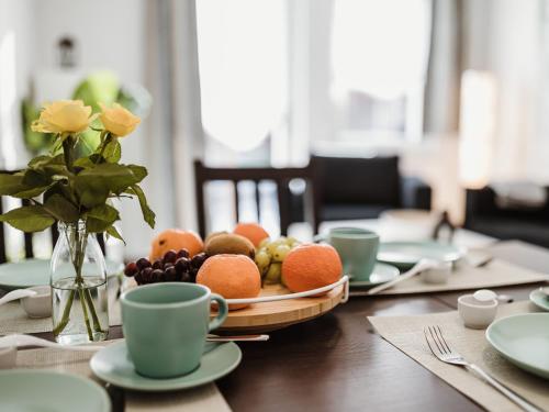 una mesa con un bol de frutas y tazas. en REBENTISCH - Hotel FERIENWOHNUNGEN Restaurant, en Hasselfelde