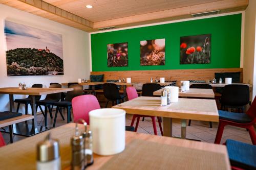un restaurante con mesas y sillas de madera y paredes verdes en Stadtplatz23 B&B en Bogen