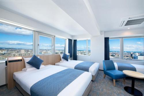 two beds in a hotel room with large windows at ART HOTEL Miyazaki Sky Tower in Miyazaki