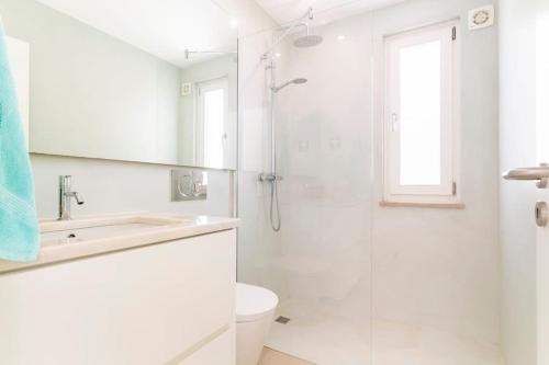 a white bathroom with a shower and a sink at Casa Hortas in Vila do Bispo