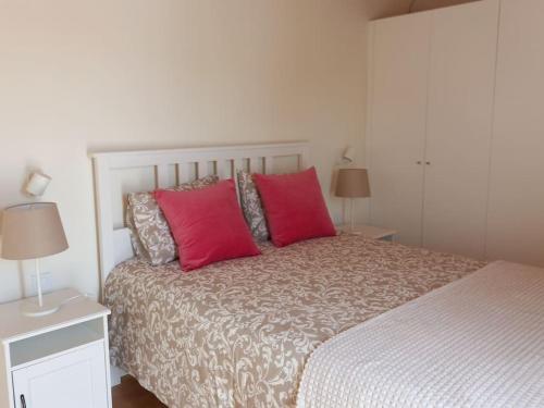 a bedroom with a large bed with two red pillows at Casa Hortas in Vila do Bispo