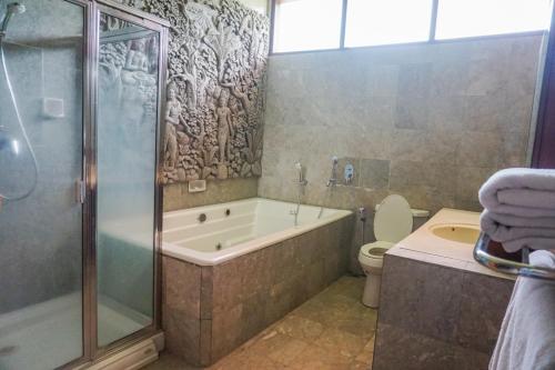 a bathroom with a tub and a toilet and a shower at Villa Biyu Siyu in Ubud