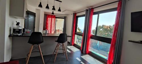 a kitchen with two stools and a counter with windows at Résidence Amarosa in Les Avirons
