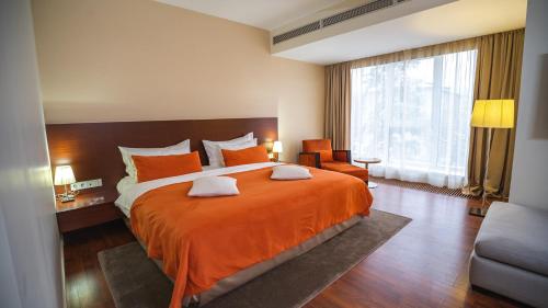 a bedroom with a large bed with an orange bedspread at Park Hotel Almaty in Almaty