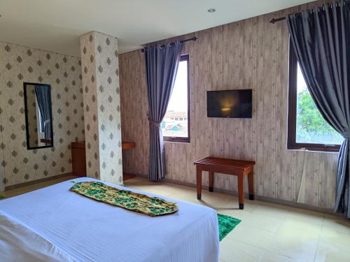 Schlafzimmer mit einem Bett, einem Tisch und Fenstern in der Unterkunft HOTEL NALENDRA PLAZA SUBANG in Subang