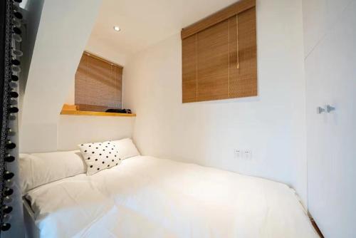a white room with a bed and a window at Shanghai Hills & Serendipity Roof House in Shanghai