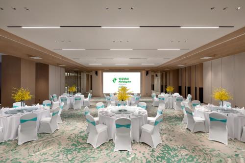 a conference room with white tables and chairs and a screen at Holiday Inn Quanzhou Donghai by IHG in Quanzhou