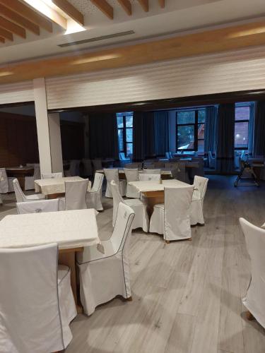 a dining room with white tables and white chairs at Hotel Pahuljica in Vlasic