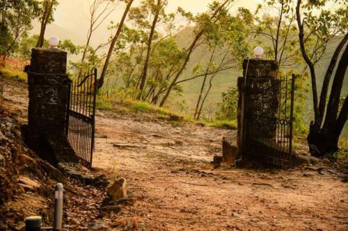 an iron gate on a dirt road with trees at Eastland Bungalow, Hewaheta, Kandy in Hewaheta