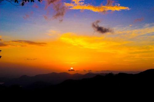 a sunset with the sun setting over the mountains at Eastland Bungalow, Hewaheta, Kandy in Hewaheta