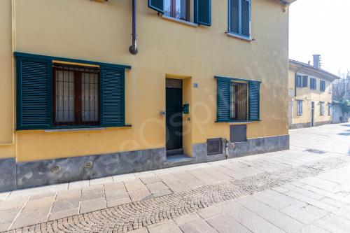 a yellow building with blue shutters on a street at CaseOspitali - Casa Klimt, rinnovato bilocale in centro storico per 4 in Cernusco sul Naviglio