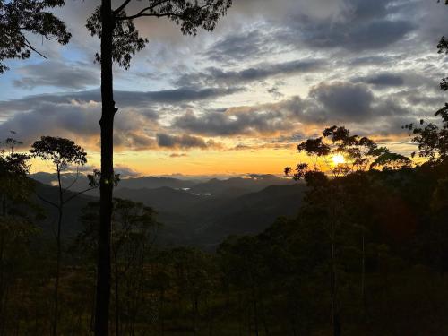 a sunset in the mountains with trees in the foreground at Eastland Bungalow, Hewaheta, Kandy in Hewaheta
