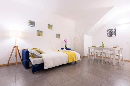Dormitorio blanco con cama y mesa en CaseOspitali - CASA KLIMT rinnovato bilocale in centro storico per 4 pax, en Cernusco sul Naviglio