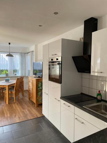 a kitchen with white cabinets and a dining room at Meyers Veranda in Zingst