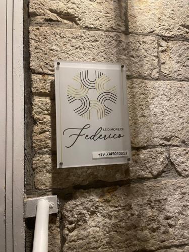 una señal en el costado de una pared de ladrillo en Le Dimore di Federico - Trani, en Trani